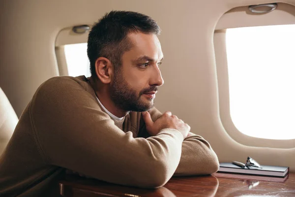 Hombre barbudo guapo sentado en primera clase de jet privado - foto de stock