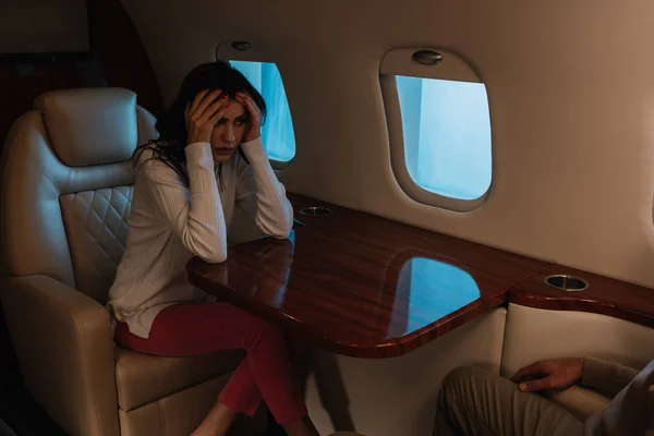 Обрезанный вид мужчины, сидящего рядом с напуганной женщиной со страхом полета в частном самолете — стоковое фото