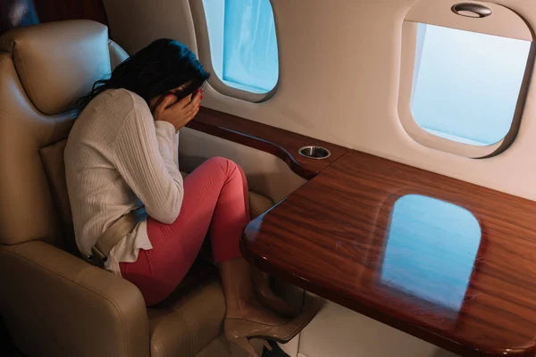 Femme effrayée avec le visage de couverture de mal de l'air tout en étant assis dans un jet privé — Photo de stock