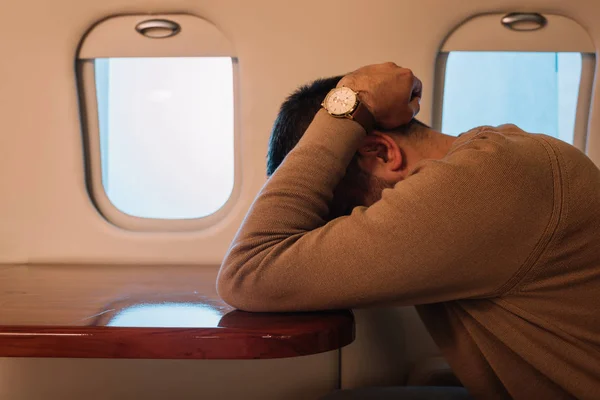 Scared man with airsickness covering face in private jet — Stock Photo