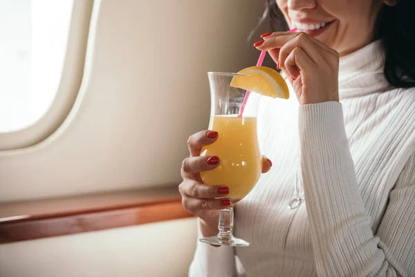 Cropped view of woman holding tasty cocktail in private jet — Stock Photo