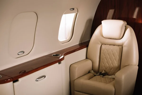 Солнечный свет на кожаном сиденье возле окна самолета в частном самолете — стоковое фото