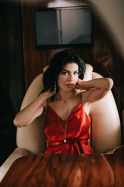 Selective focus of attractive woman in red dress sitting in private jet — Stock Photo