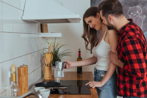 Jovem homem tocando feliz namorada fazendo café em geyser cafeteira — Fotografia de Stock