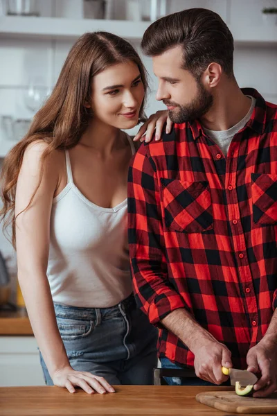 Feliz, hermosa chica mirando guapo novio corte fresco aguacate - foto de stock