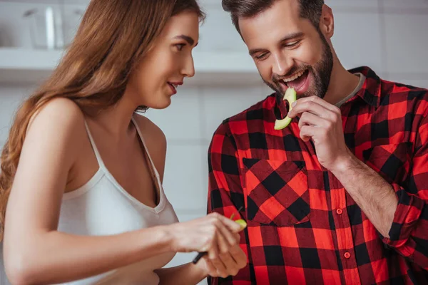 Веселий чоловік дегустує шматочок свіжого авокадо біля привабливої дівчини — стокове фото