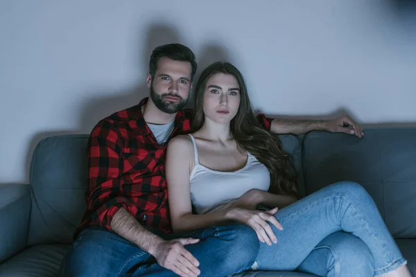 Joven, pareja concentrada viendo la televisión en el sofá en casa - foto de stock