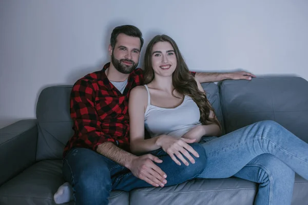 Jeune, couple joyeux regarder la télévision sur le canapé à la maison — Photo de stock