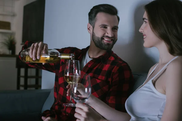 Feliz chica sosteniendo gafas mientras alegre hombre verter vino - foto de stock