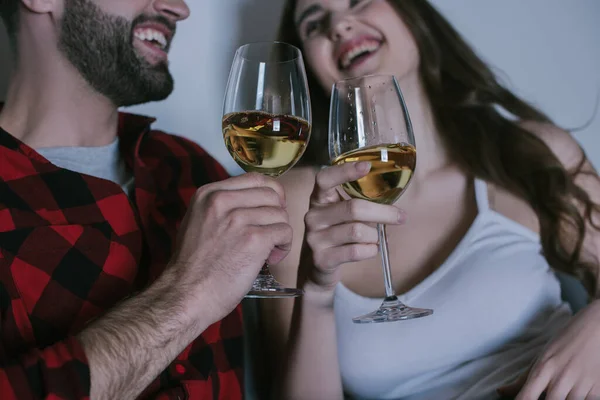 Selective focus of young couple laughing while holding glasses of white wine — Stock Photo