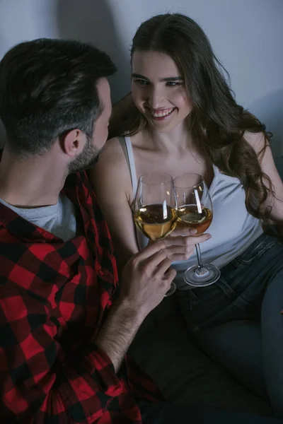 Vista de ángulo alto de alegre chica tintineo vasos de vino blanco con novio - foto de stock