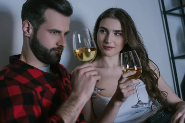 Sonriente chica mirando soñador novio mientras sentado junto con copas de vino blanco - foto de stock