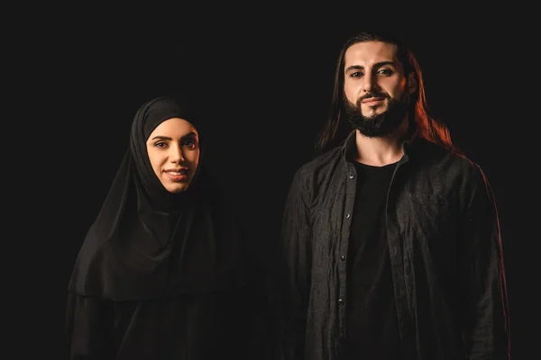 Smiling muslim couple looking at camera isolated on black — Stock Photo