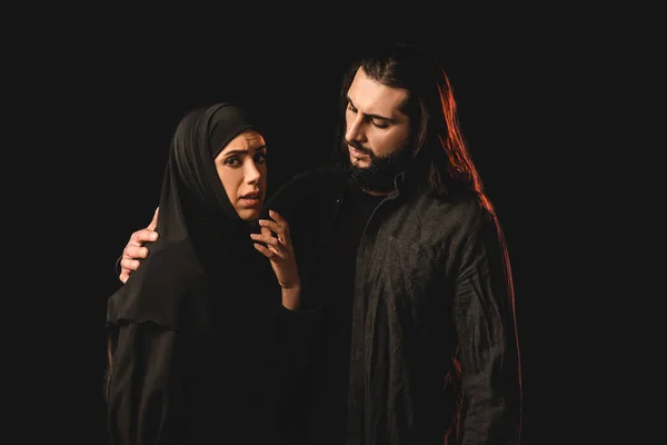 Muslim man embracing worried wife isolated on black — Stock Photo