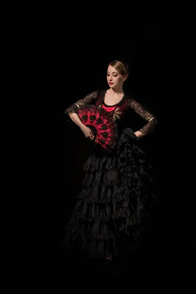 Beautiful dancer holding fan while dancing flamenco isolated on black — Stock Photo