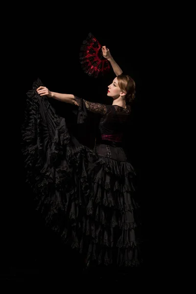 Beautiful young dancer holding fan while dancing flamenco isolated on black — Stock Photo