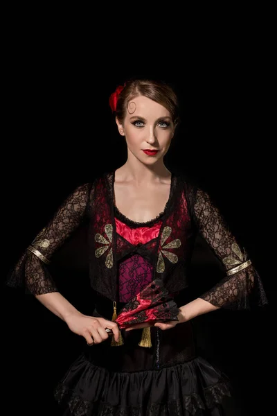 Beautiful flamenco dancer holding fan and looking at camera isolated on black — Stock Photo