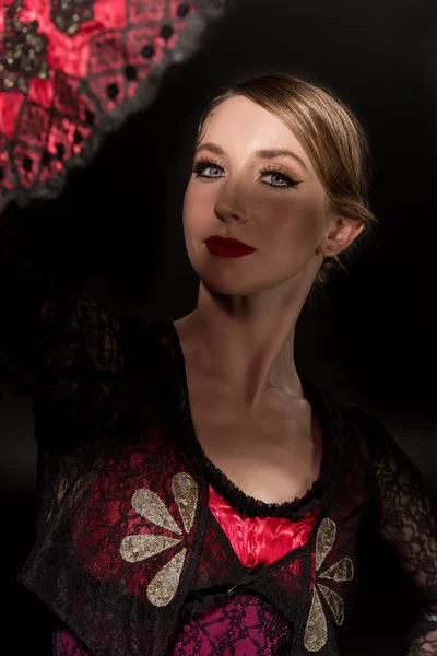 Selective focus of pretty flamenco dancer looking at camera near fan isolated on black — Stock Photo