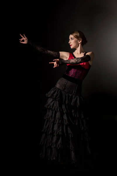 Elegant woman gesturing and dancing flamenco on black — Stock Photo
