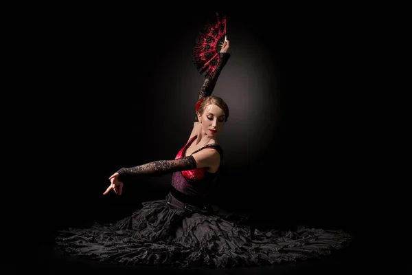 Jovem dançarina de flamenco segurando ventilador enquanto sentado em preto — Fotografia de Stock