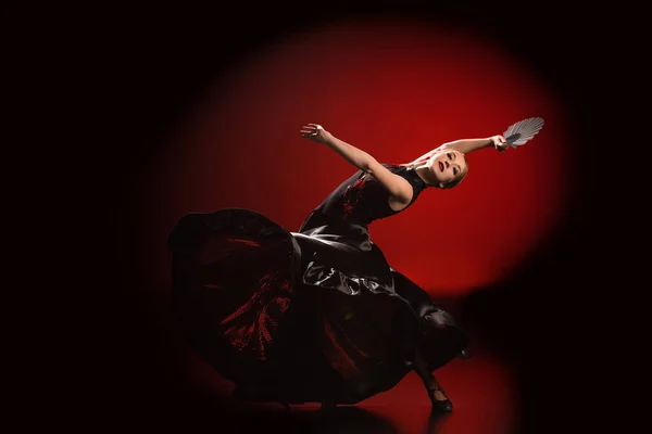 Jovem dançarina de flamenco no vestido segurando fã enquanto dança em vermelho e preto — Fotografia de Stock