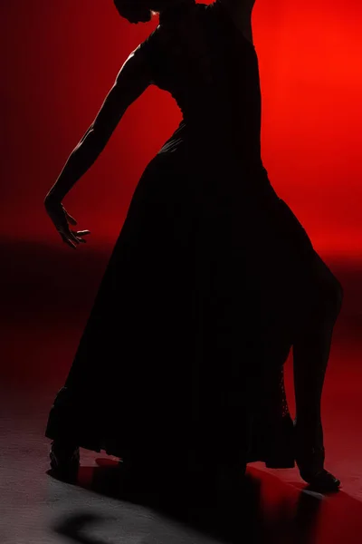 Vista recortada de mujer joven y elegante bailando flamenco sobre rojo - foto de stock