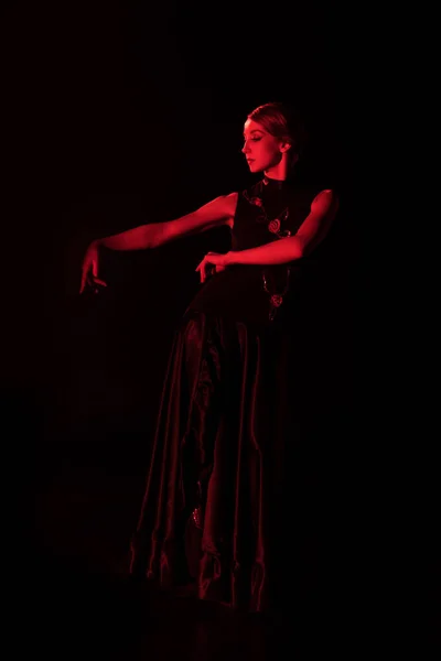 Rotes Licht an Flamenco-Tänzerin im Kleid, die isoliert auf Schwarz tanzt — Stockfoto