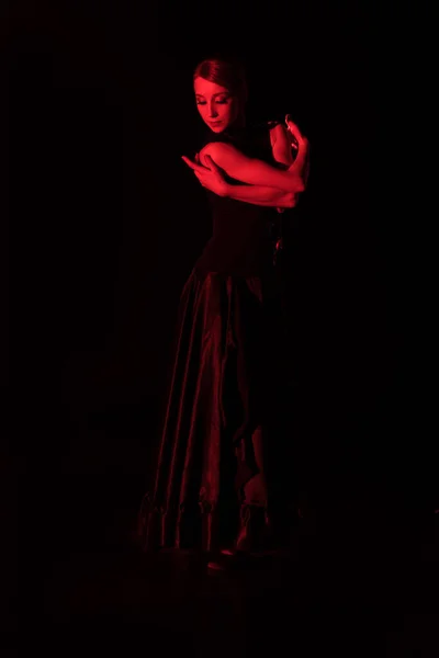 Красное освещение элегантной женщины танцующей фламенко изолированы на черный — стоковое фото