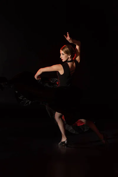 Pretty young dancer dancing flamenco on black — Stock Photo