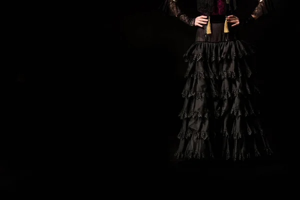 Cropped view of young flamenco dancer standing with hands on hips isolated on black — Stock Photo