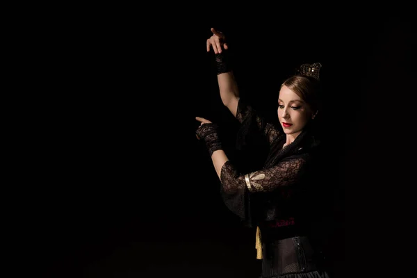 Dançarina de flamenco elegante dançando e gesticulando enquanto olha para baixo isolado em preto — Fotografia de Stock