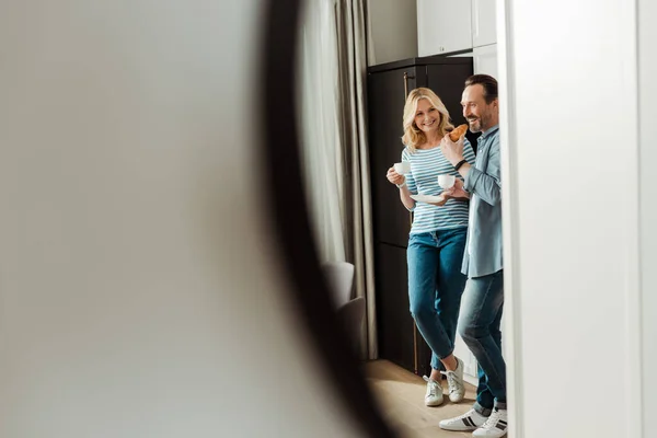 Enfoque selectivo de pareja sonriente con croissant y café reflejándose en espejo - foto de stock