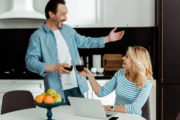 Focus selettivo di allegra coppia matura clinking con vino in cucina — Foto stock