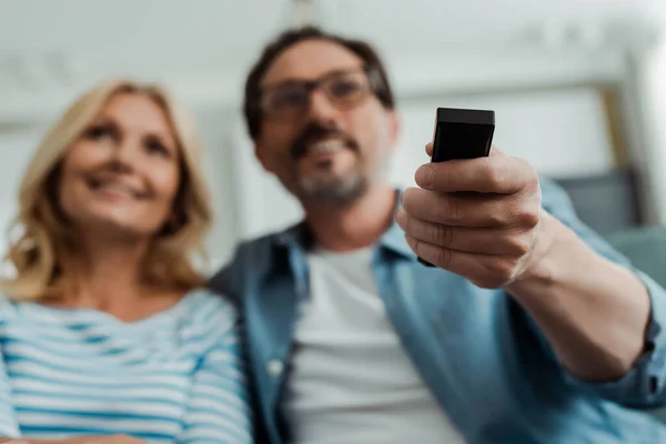 Selektiver Fokus des Mannes, der Fernbedienung in der Nähe seiner Frau zu Hause hält — Stockfoto