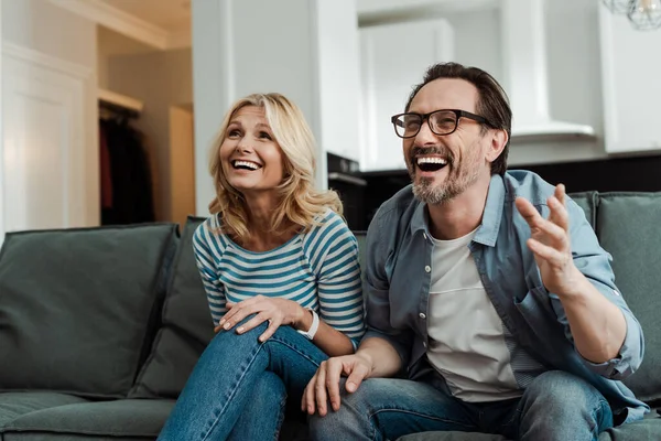 Pareja madura riendo mientras está sentada en el sofá - foto de stock