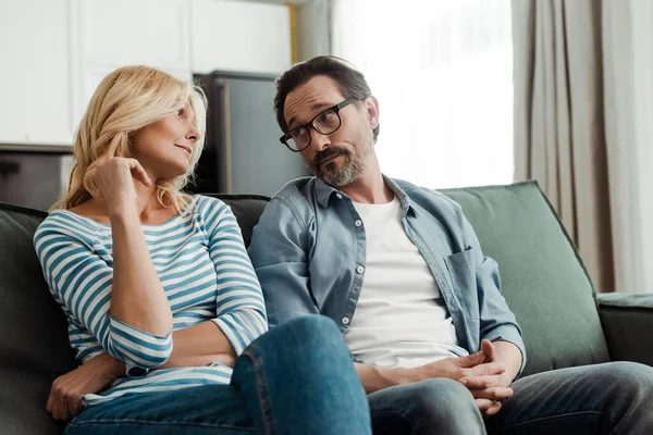 Selektiver Fokus eines hübschen reifen Mannes, der seine schöne Frau auf dem Sofa anschaut — Stockfoto