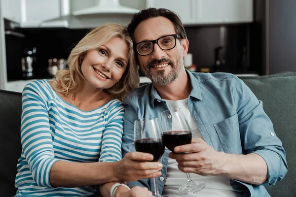 Улыбающаяся зрелая пара пьет вино дома — стоковое фото