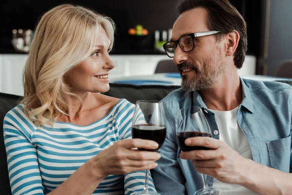 Schöne Frau lächelt Mann an, während sie zu Hause mit Wein anstößt — Stockfoto