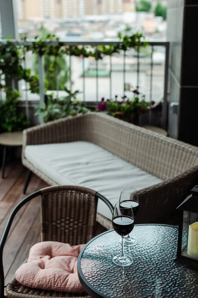 Copos de vinho na mesa perto do sofá de vime no terraço — Fotografia de Stock