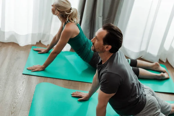 Enfoque selectivo de pareja adulta haciendo ejercicio en colchonetas de fitness en casa - foto de stock