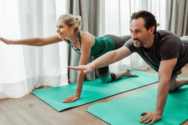 Sorridente coppia matura esercizio su stuoie fitness in soggiorno — Foto stock