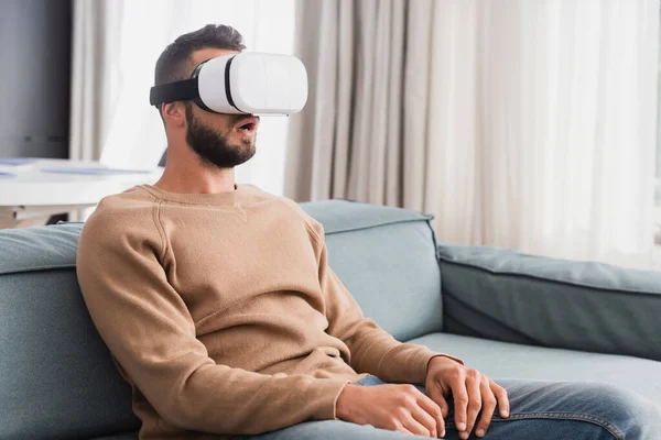 Uomo sorpreso in realtà virtuale auricolare in salotto — Foto stock