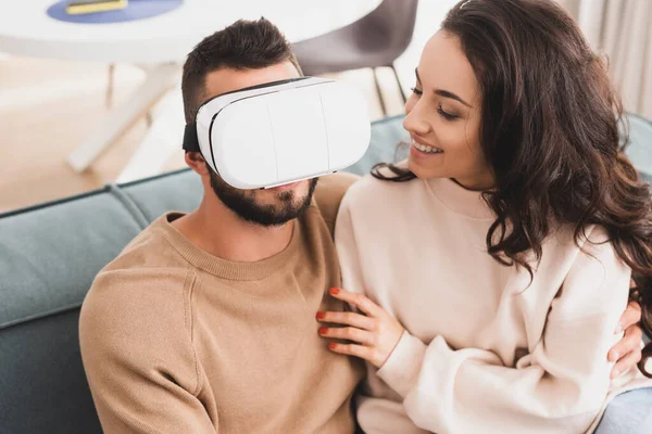 Счастливая девушка смотрит на бородатого бойфренда в гарнитуре виртуальной реальности — стоковое фото