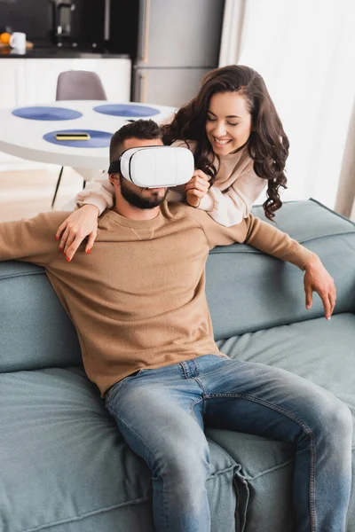 Веселая девушка смотрит на бородатого парня в наушниках виртуальной реальности — стоковое фото