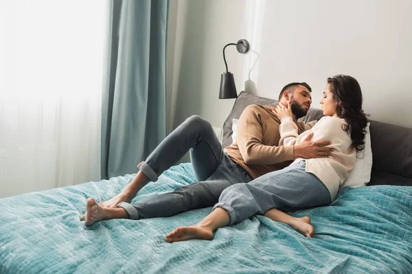 Beautiful girl and handsome man with closed eyes embracing while lying on bed — Stock Photo