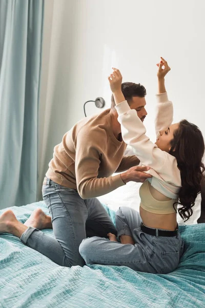 Seitenansicht eines bärtigen Mannes, der schöne Mädchen im Schlafzimmer auszieht — Stockfoto