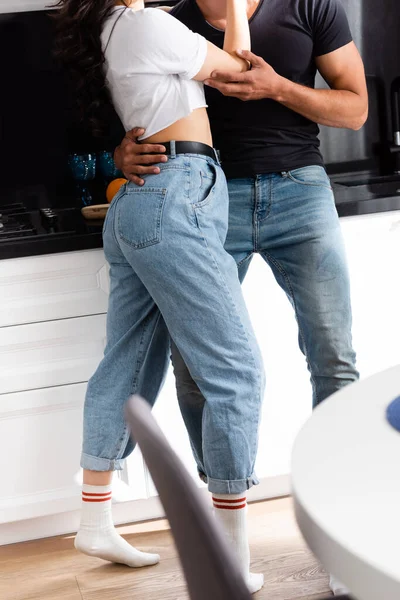 Recortado vista de hombre abrazando joven mujer en jeans - foto de stock