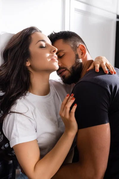 Bearded man hugging attractive girlfriend with closed eyes — Stock Photo