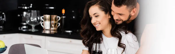 Panoramic concept of happy man hugging girlfriend with glass of red wine — Stock Photo