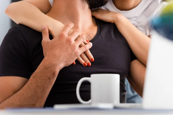Cropped view of woman touching freelancer boyfriend near laptop and cup — Stock Photo